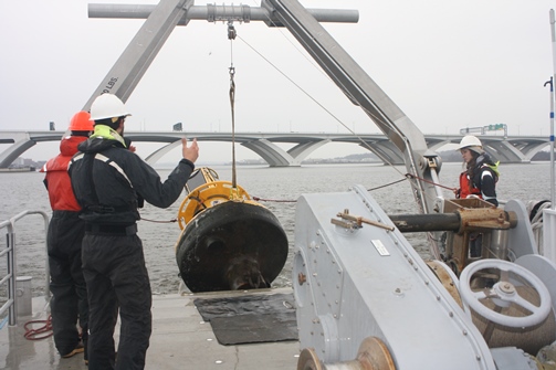 yellow buoy being pulled from the Potomac RIver onto a research vessel